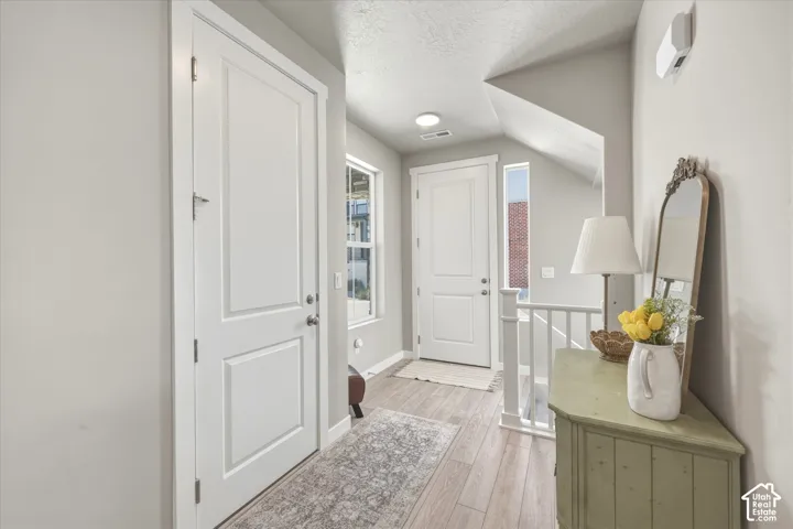 Entryway featuring wood-finish flooring, white paneled doors, and natural light from a side window