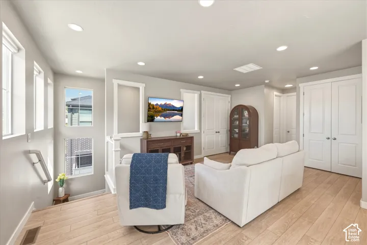 Light-filled upper-level living space featuring recessed lighting, a skylight, and light wood-finish flooring
