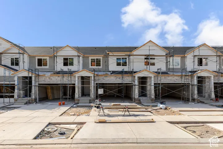 Multi-unit residential structure featuring horizontal siding, stone veneer accents, gable rooflines, and individual garage bays