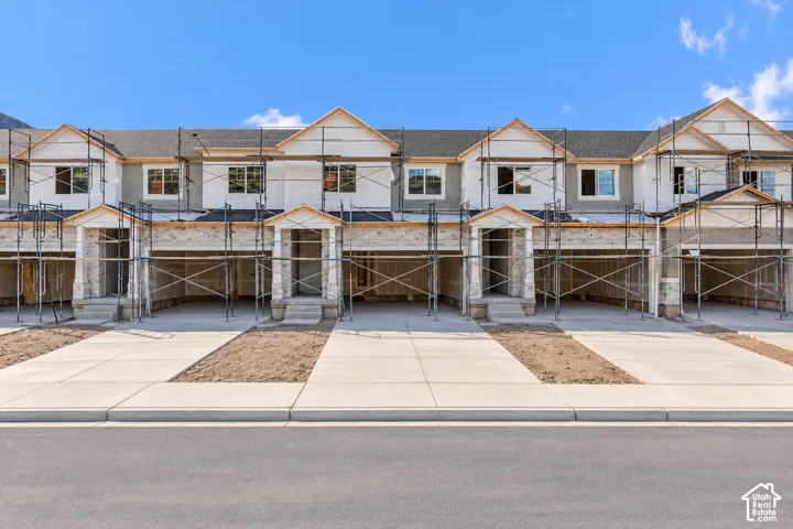 Multi-unit residential structure featuring asphalt shingle roofing, multi-gabled rooflines, stone veneer accents, and concrete driveways