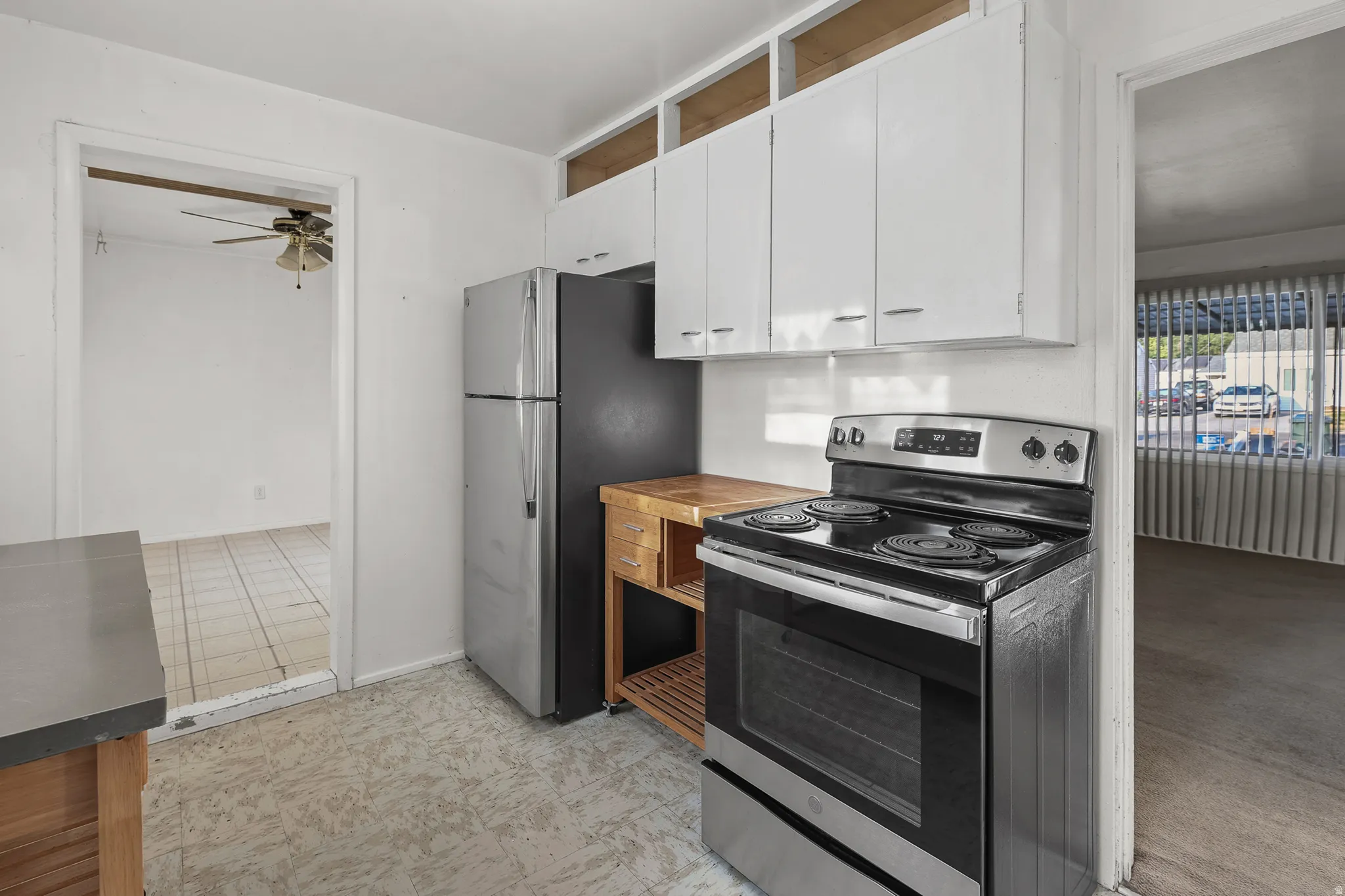 Kitchen featuring white cabinetry, a freestanding range, and a stainless steel refrigerator