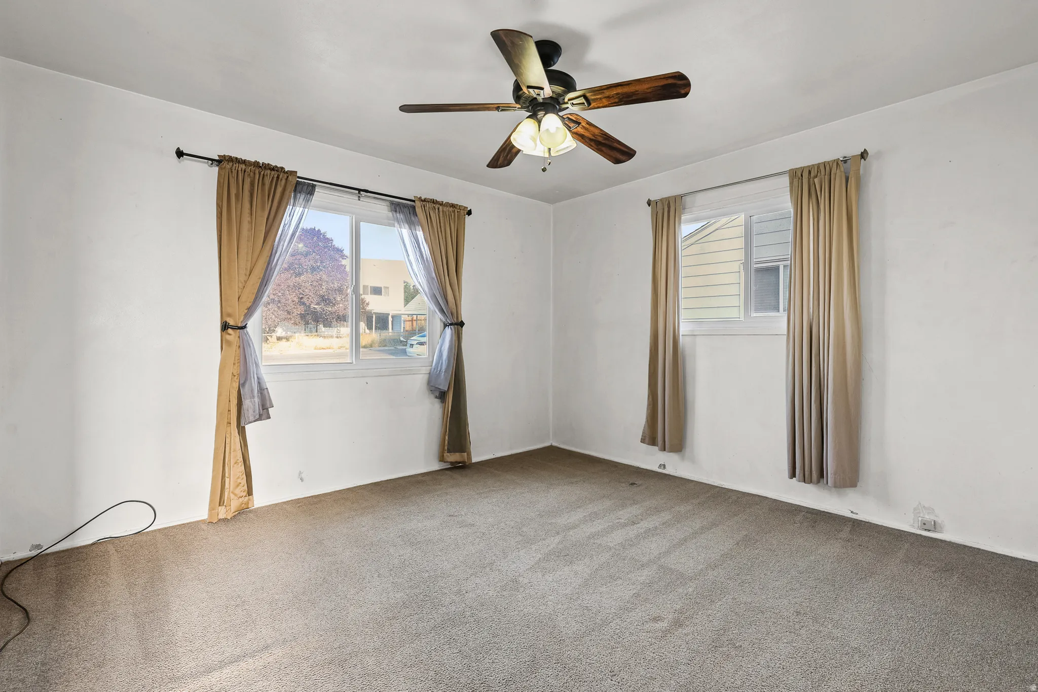 Carpeted room featuring a ceiling fan with integrated lighting and two windows