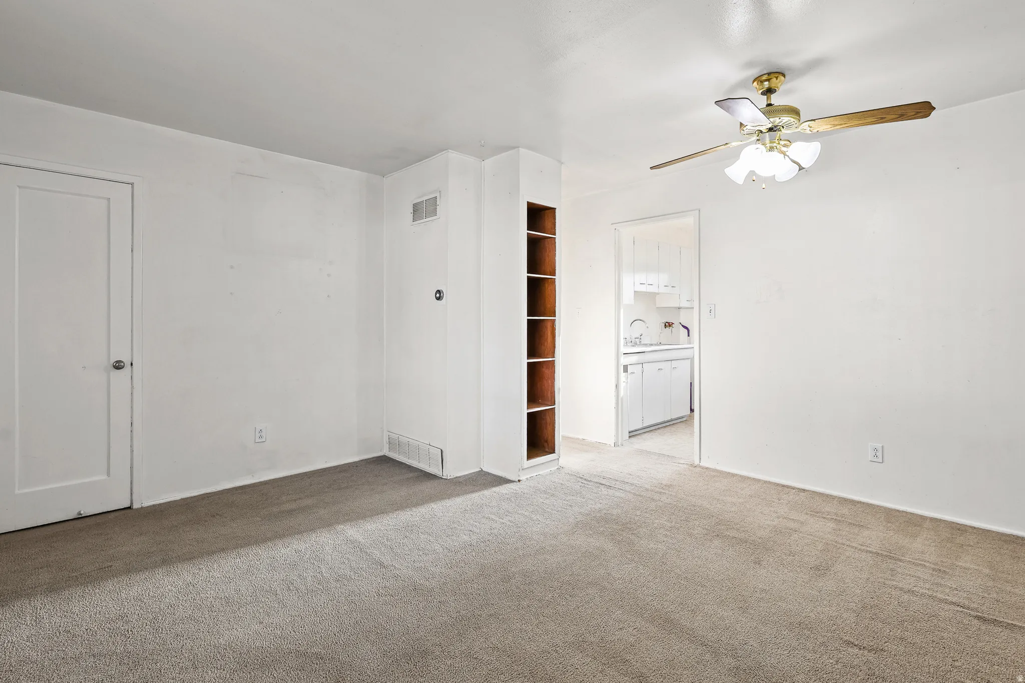 Recessed built-in shelving, ceiling fan light fixture, wall-to-wall carpeting, and white interior doors