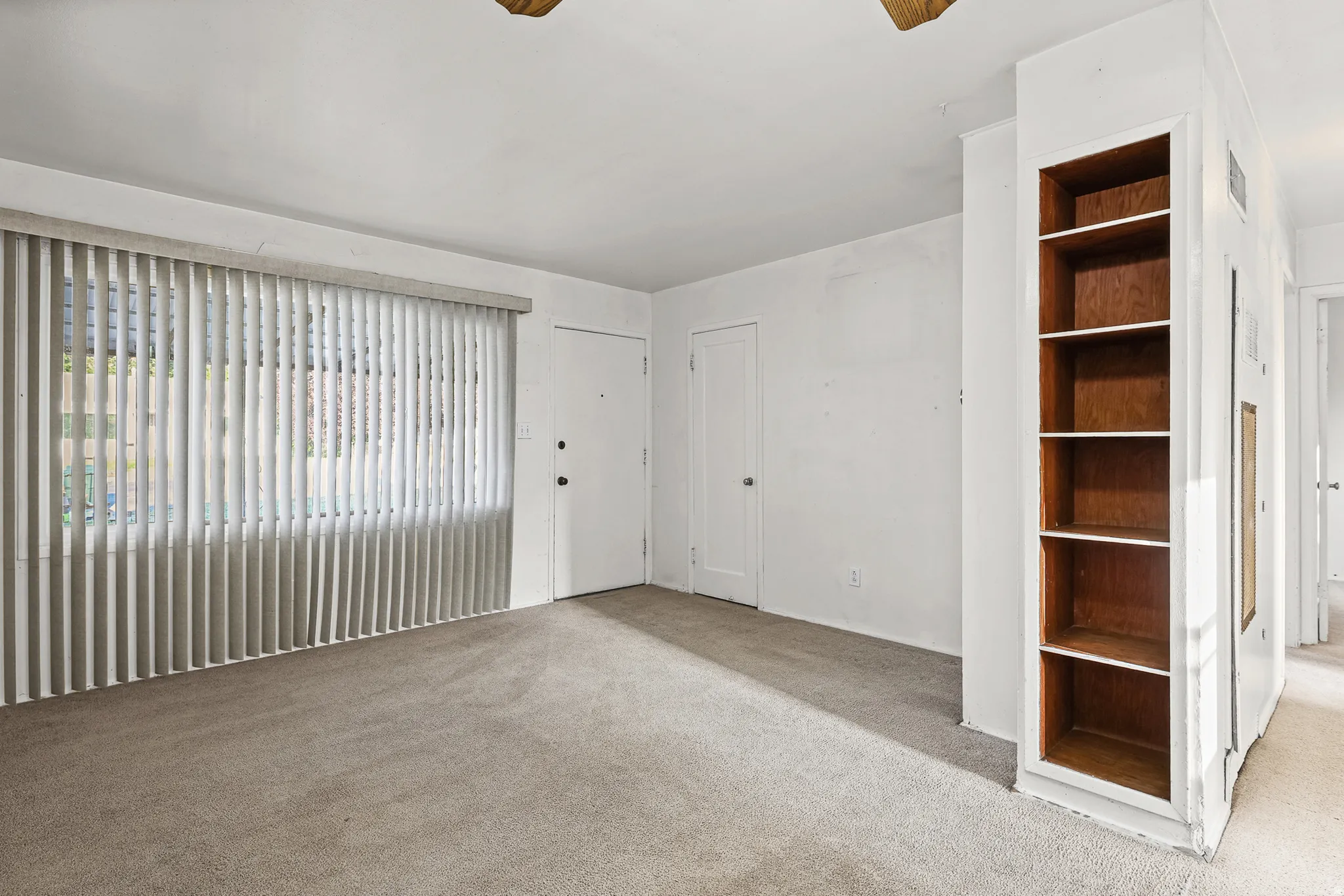 Neutral wall colors, built-in shelving, and light-colored carpeting