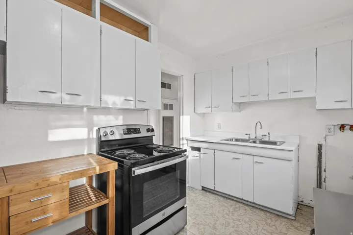 White cabinetry, stainless steel range, double basin sink, and wood-finish flooring