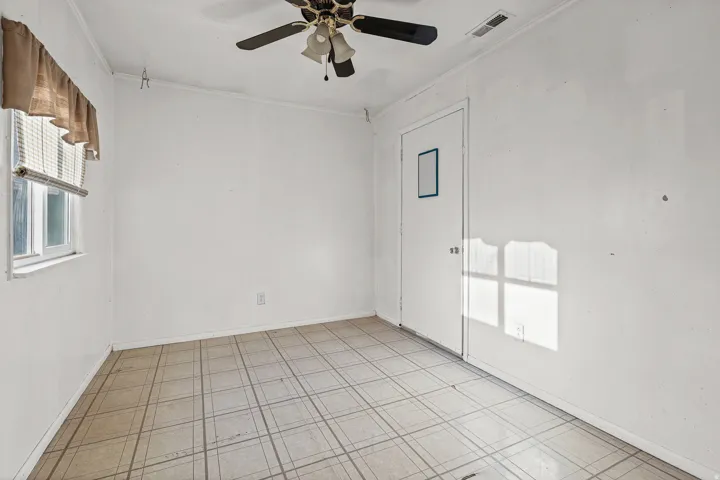 Wall-mounted ceiling fan, window with blinds, and tiled flooring