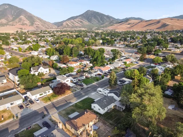 Mountainous backdrop, established residential area, tree-lined streets, varied architectural styles, and paved roadways