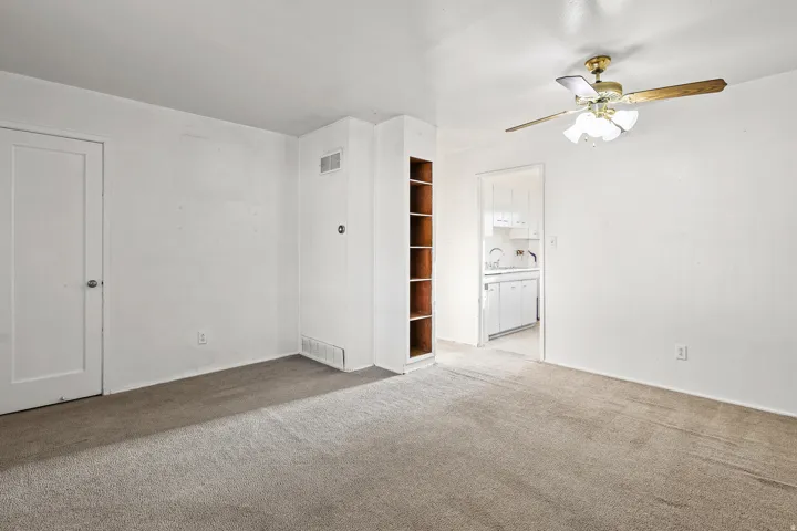Recessed built-in shelving, ceiling fan light fixture, wall-to-wall carpeting, and white interior doors