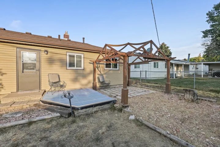 Rear exterior with siding, a brown shingle roof, and a built-in pergola over a paved patio area