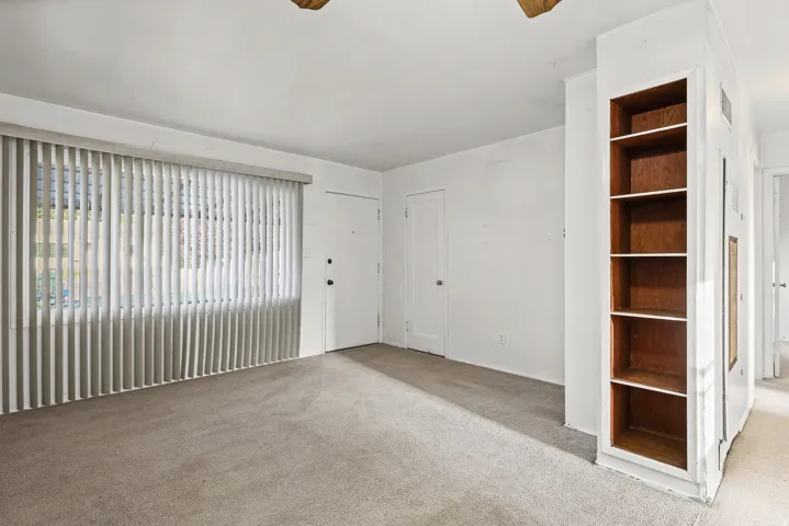 Neutral wall colors, built-in shelving, and light-colored carpeting