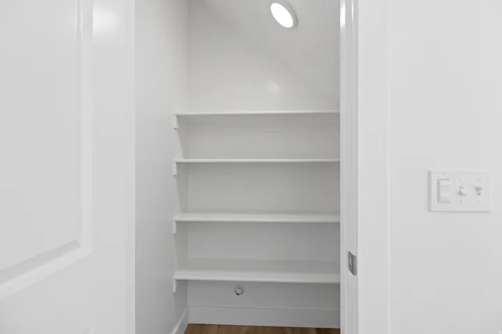 Built-in white shelving system featuring five tiers, recessed ceiling lighting, and wood-finish flooring