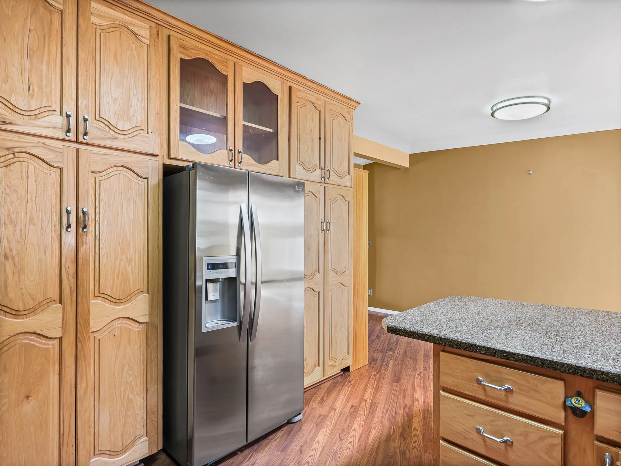 Kitchen featuring extensive wood cabinetry, a stainless steel refrigerator, and wood-finish flooring