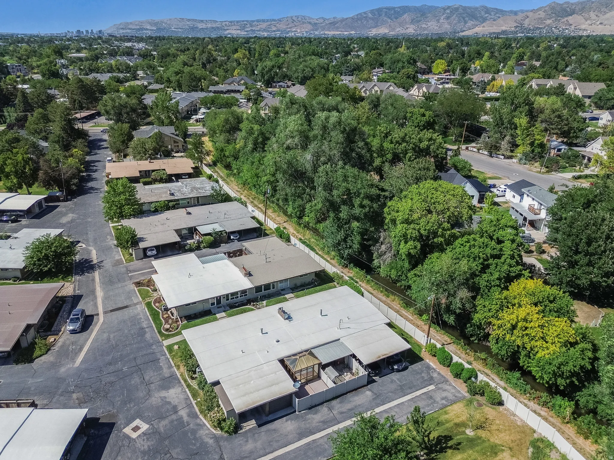 Aerial view showcasing a residential area with mature trees and mountain backdrops
