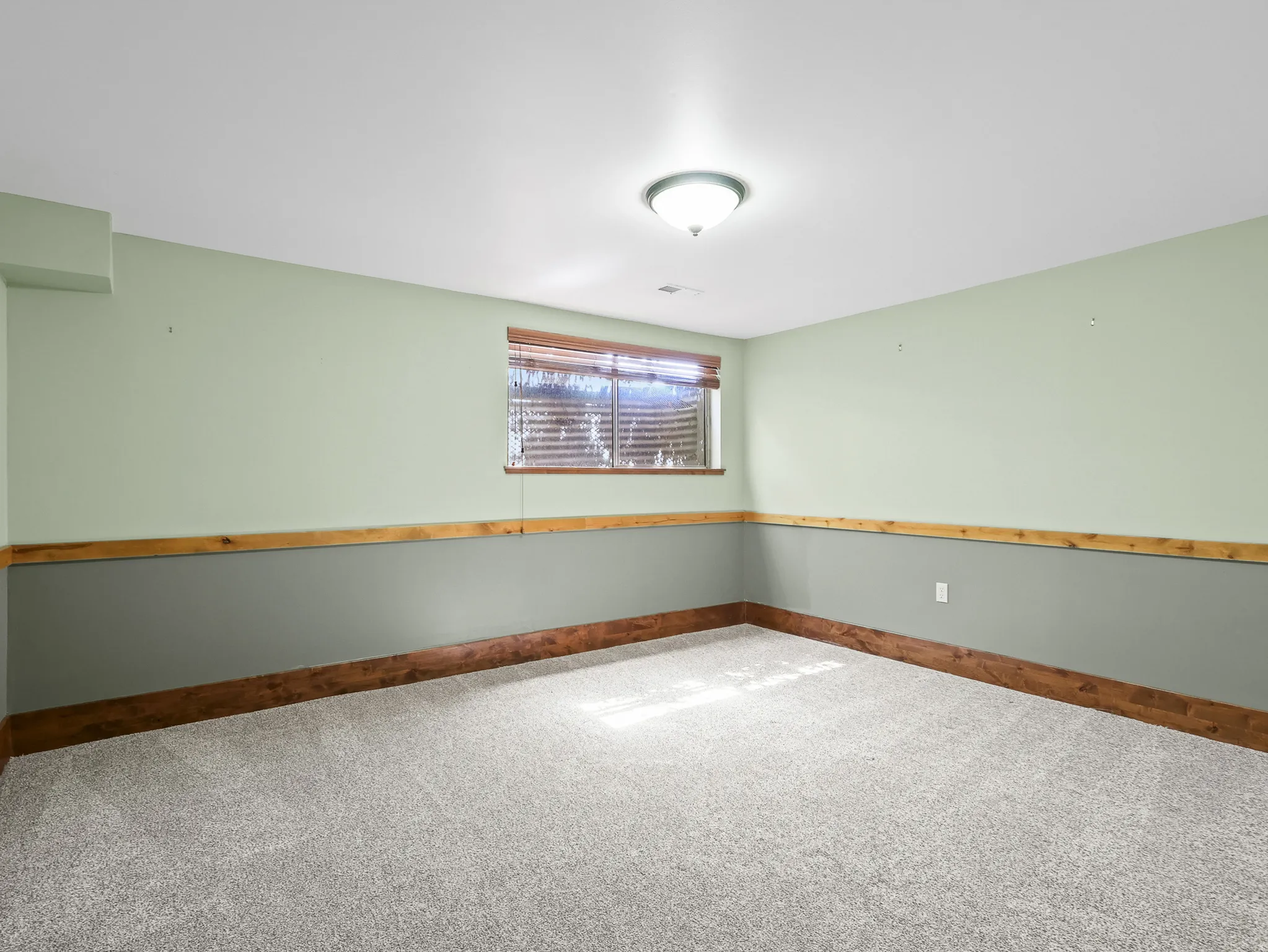 Room featuring light green and gray two-tone walls with wood trim