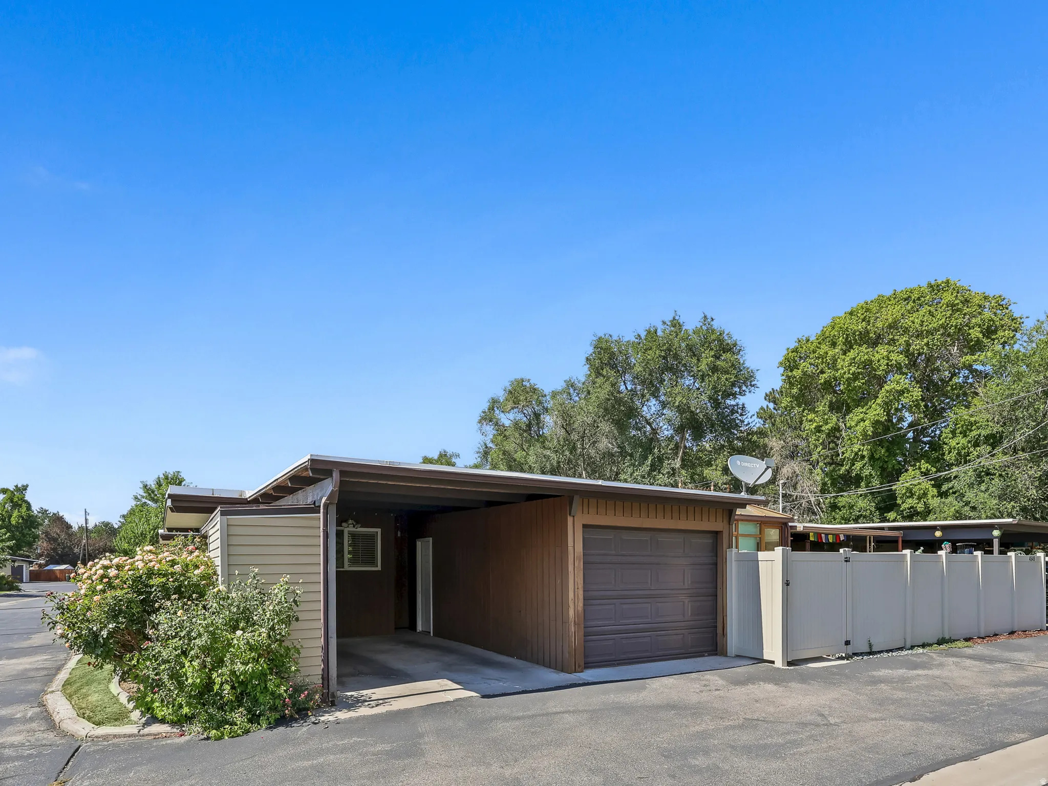 Single-story exterior featuring a carport, attached garage with a panel door, and light-colored siding