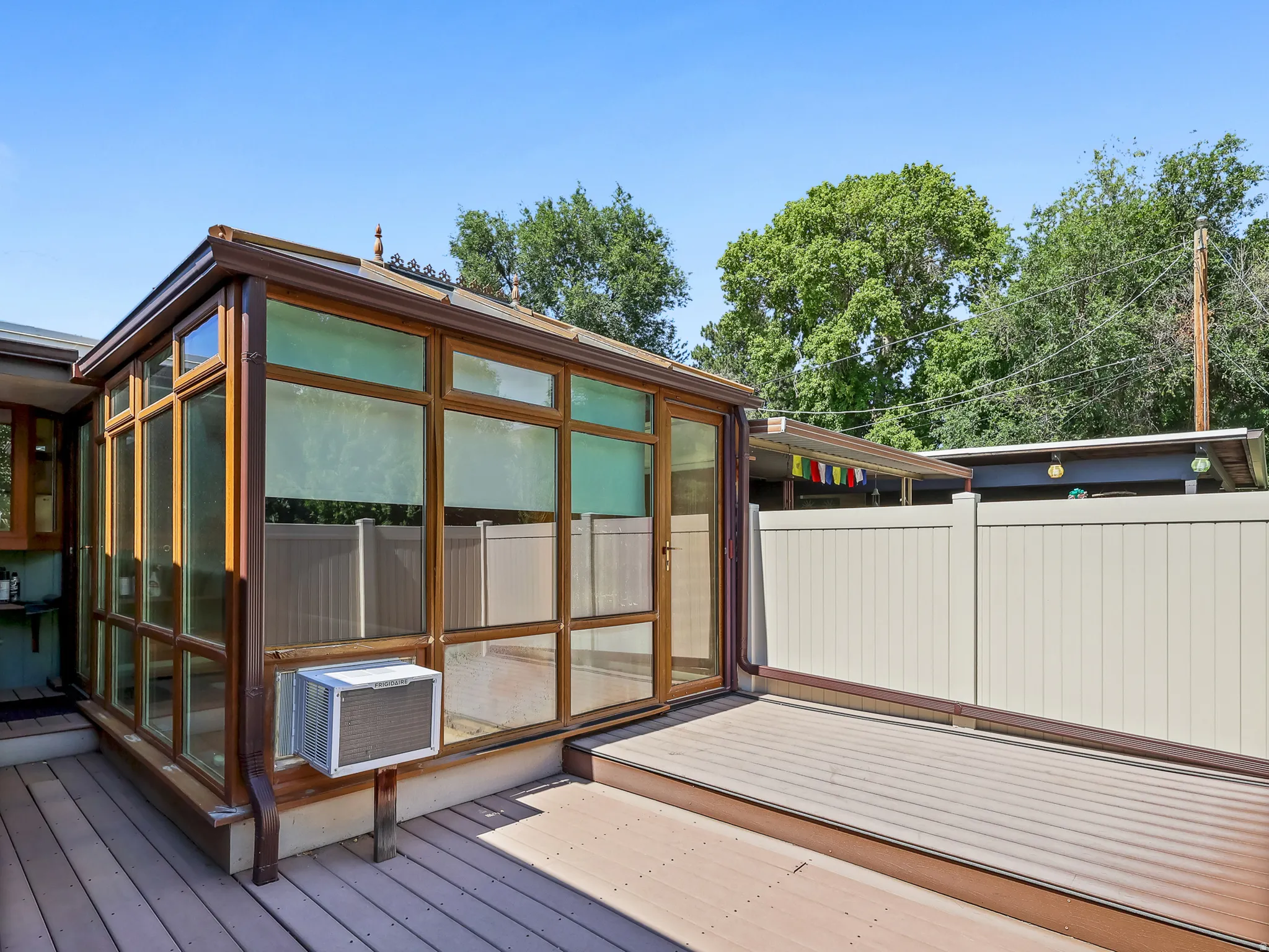 Sunroom addition featuring extensive glazing and a wood-finish frame, complemented by a multi-level deck