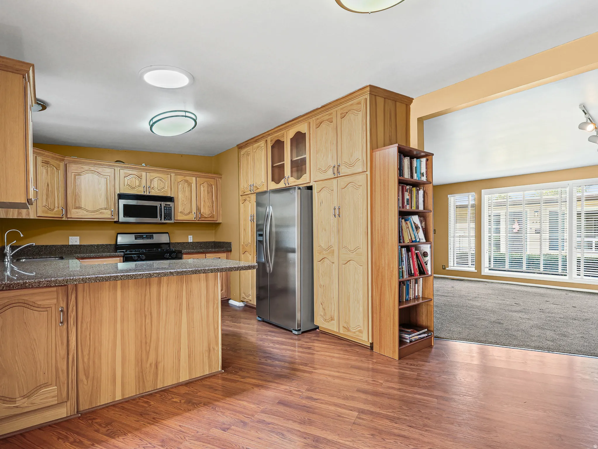 Kitchen featuring wood-finish flooring and extensive cabinetry with integrated refrigerator