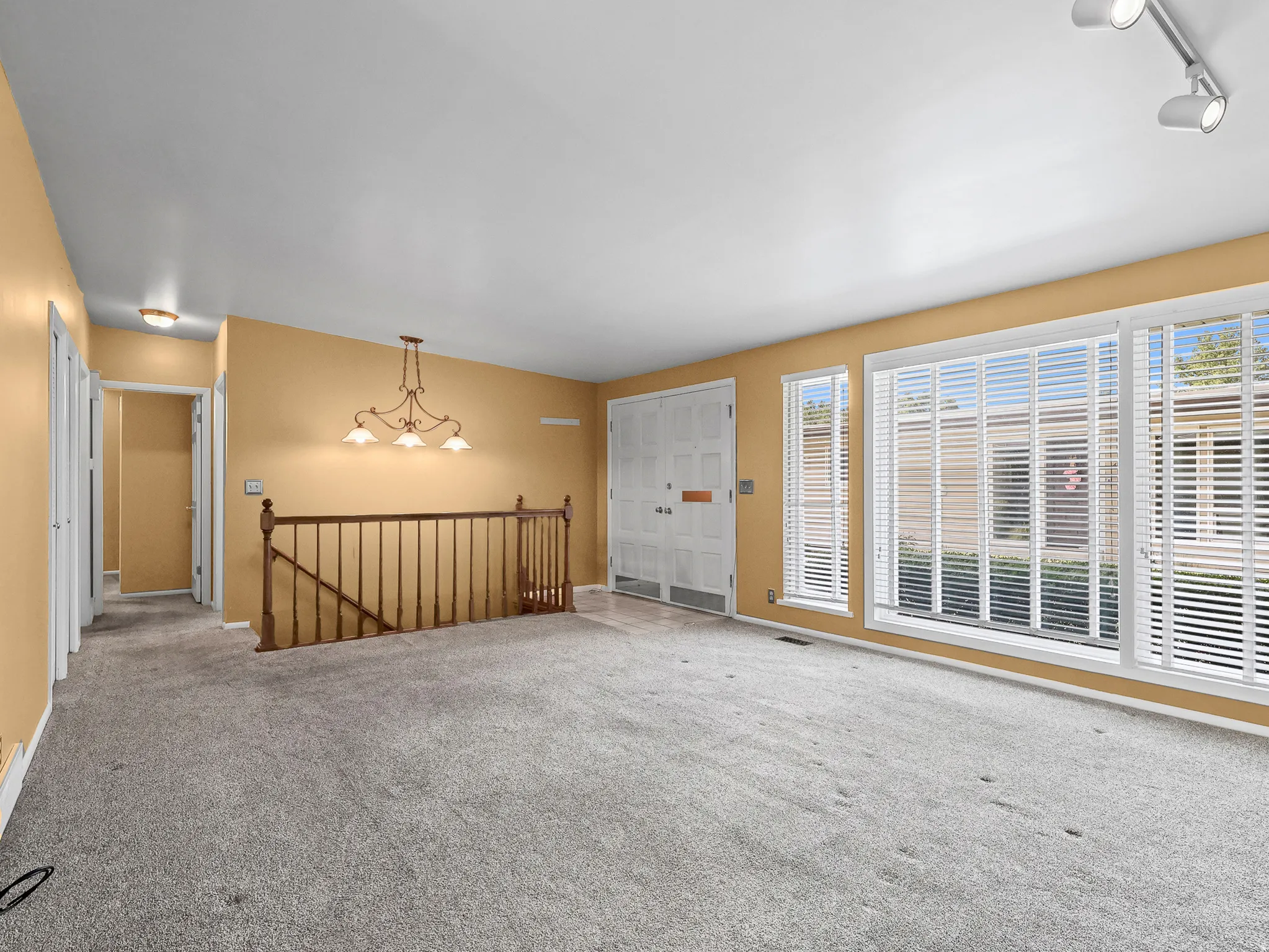 Spacious interior room featuring light-colored carpeting and warm-toned walls