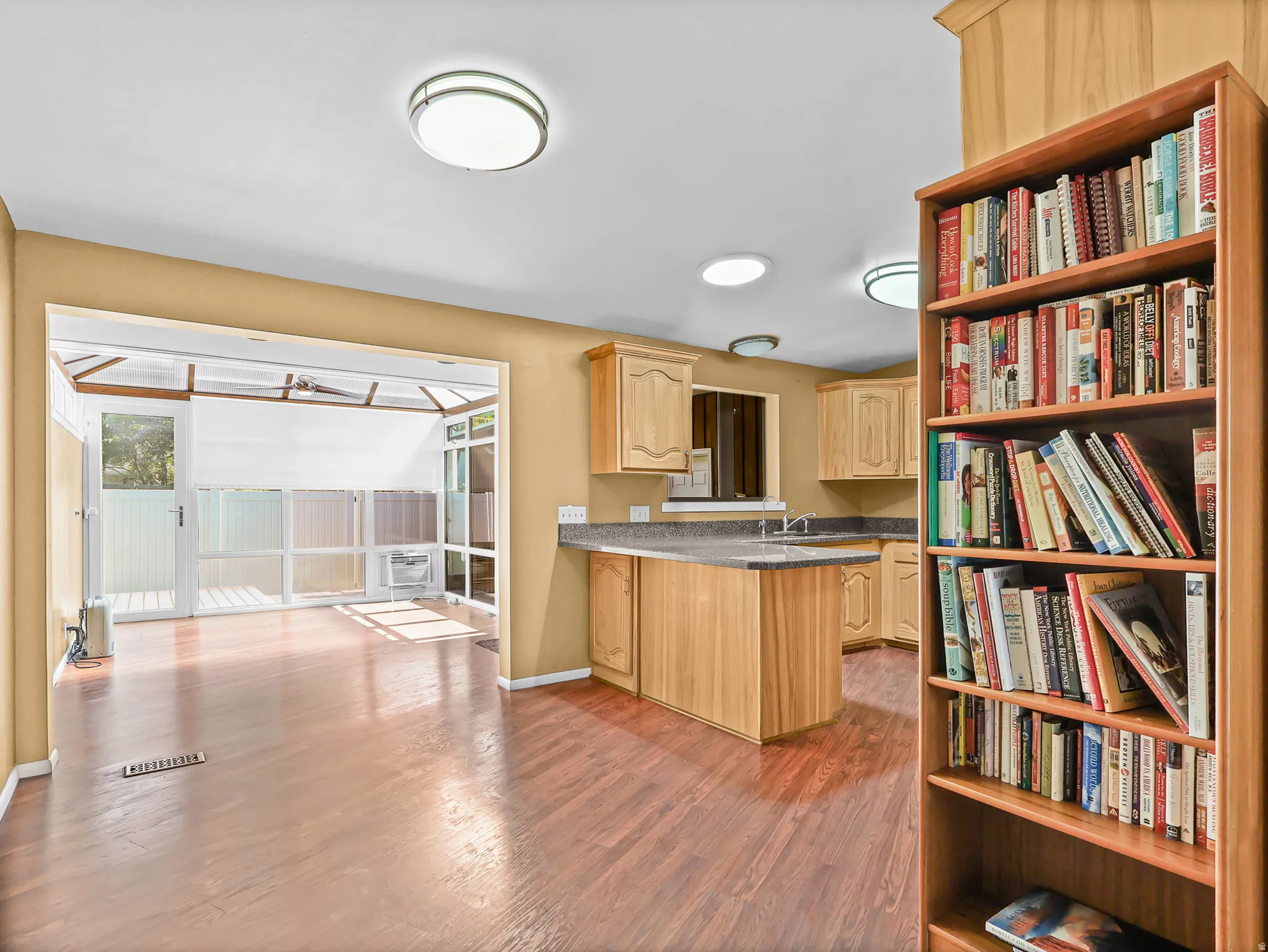 Sunroom with wood-finish flooring, white paneled walls, and a glass door