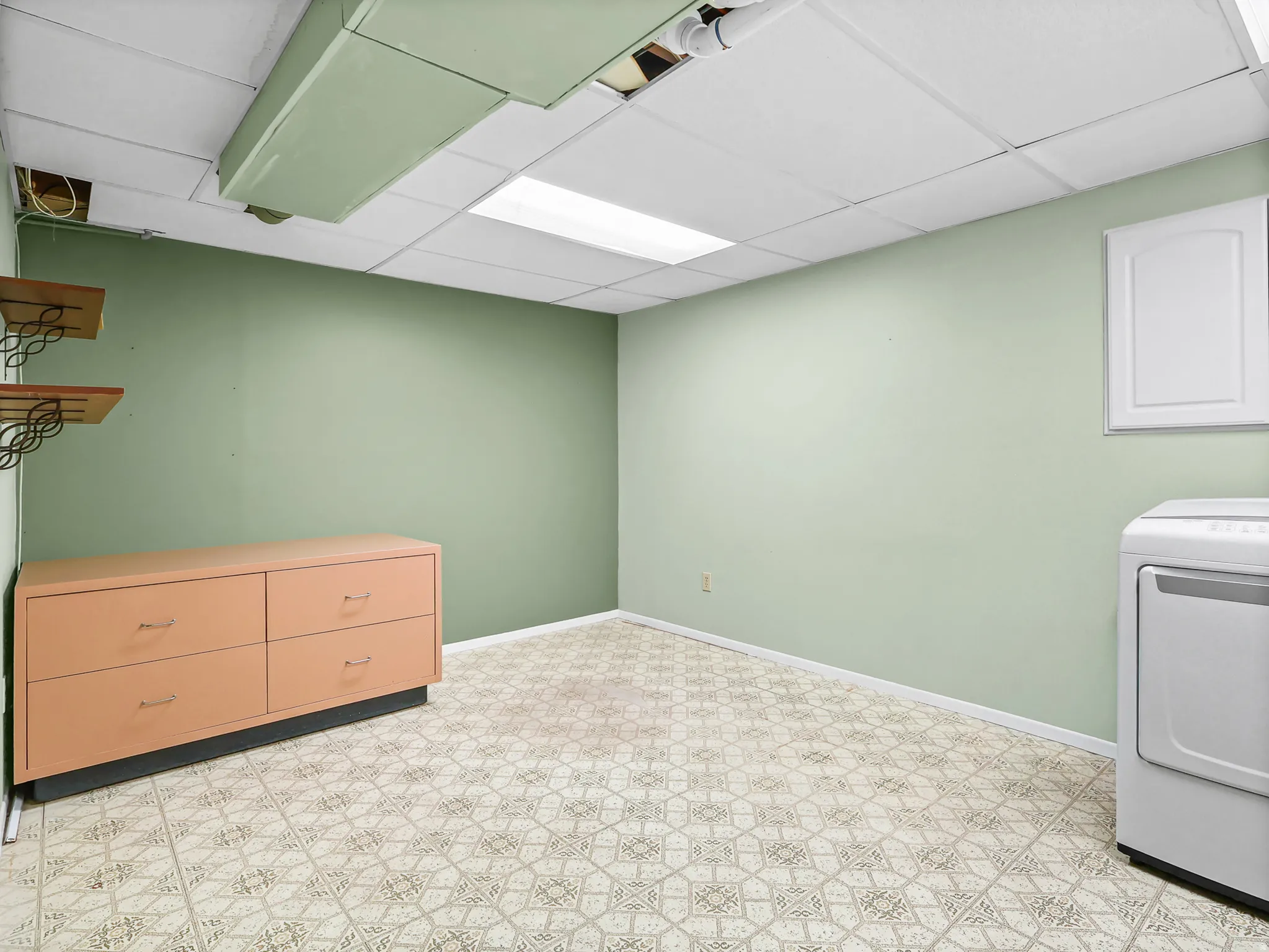 Utility space featuring patterned resilient flooring, light green walls, and a drop ceiling with integrated lighting