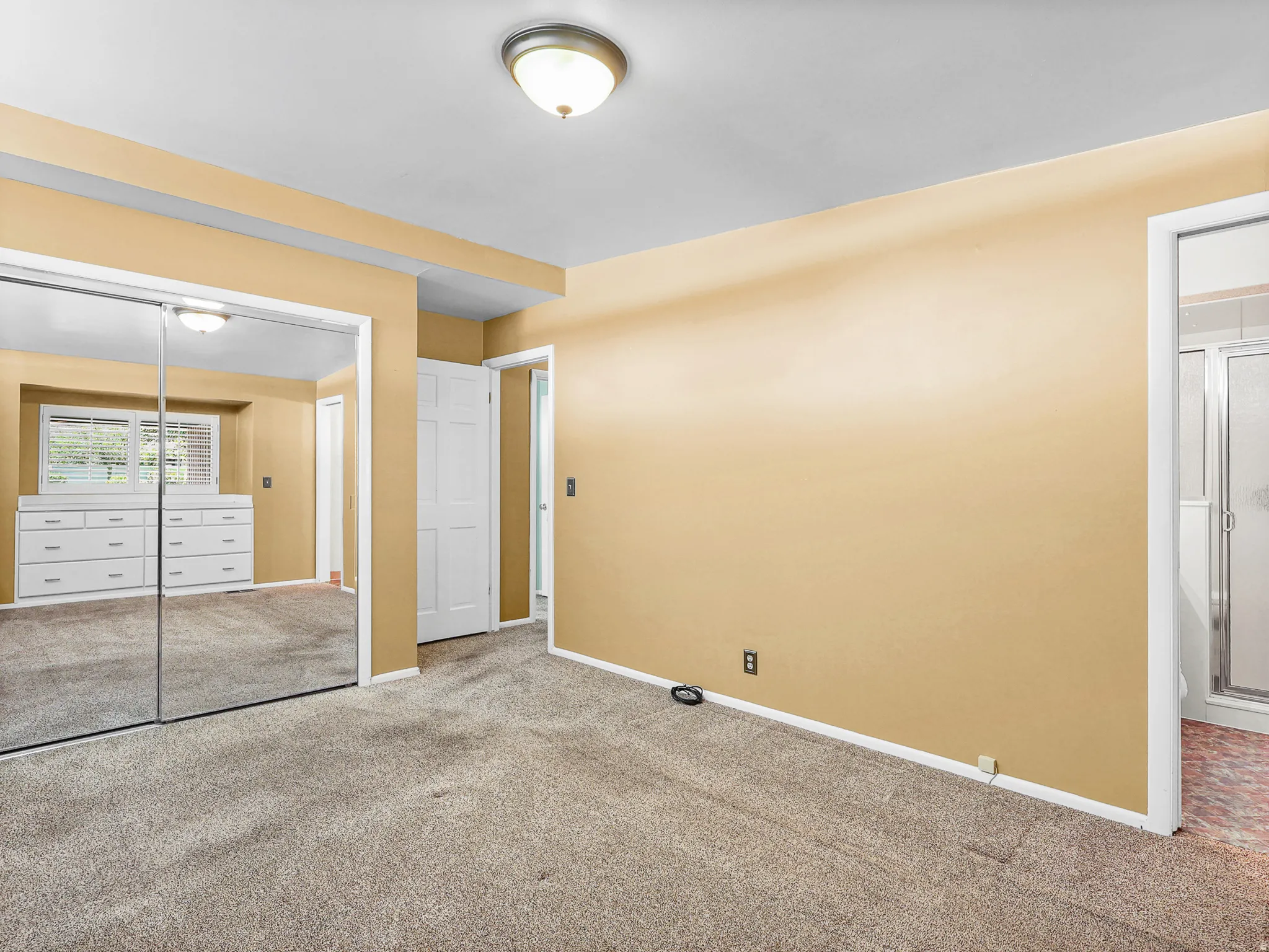 Carpeted room featuring mirrored closet doors, a built-in dresser, and an overhead flush mount light fixture