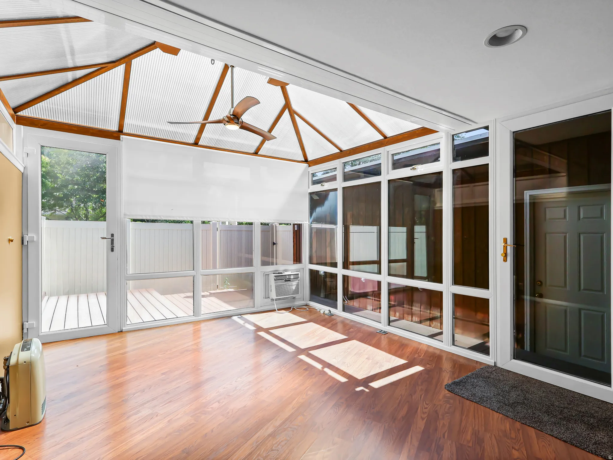 Sunroom with wood-finish flooring and a vaulted translucent ceiling