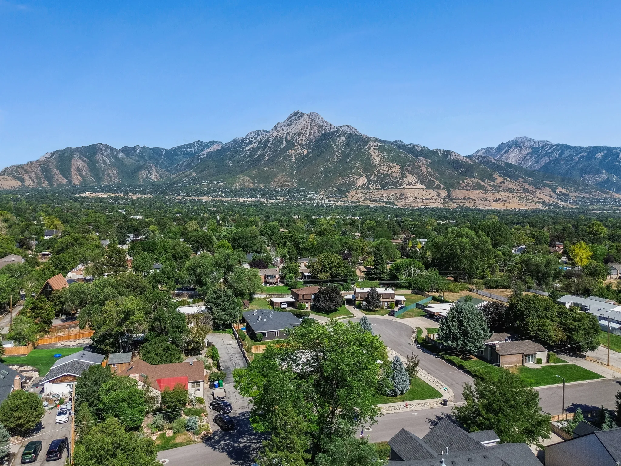 Expansive mountain range backdrop framing a residential area with mature trees and varied architectural styles