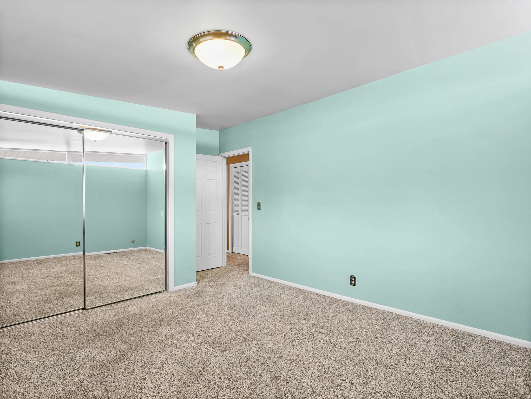 Room featuring light blue walls, neutral-toned carpet, and a white ceiling