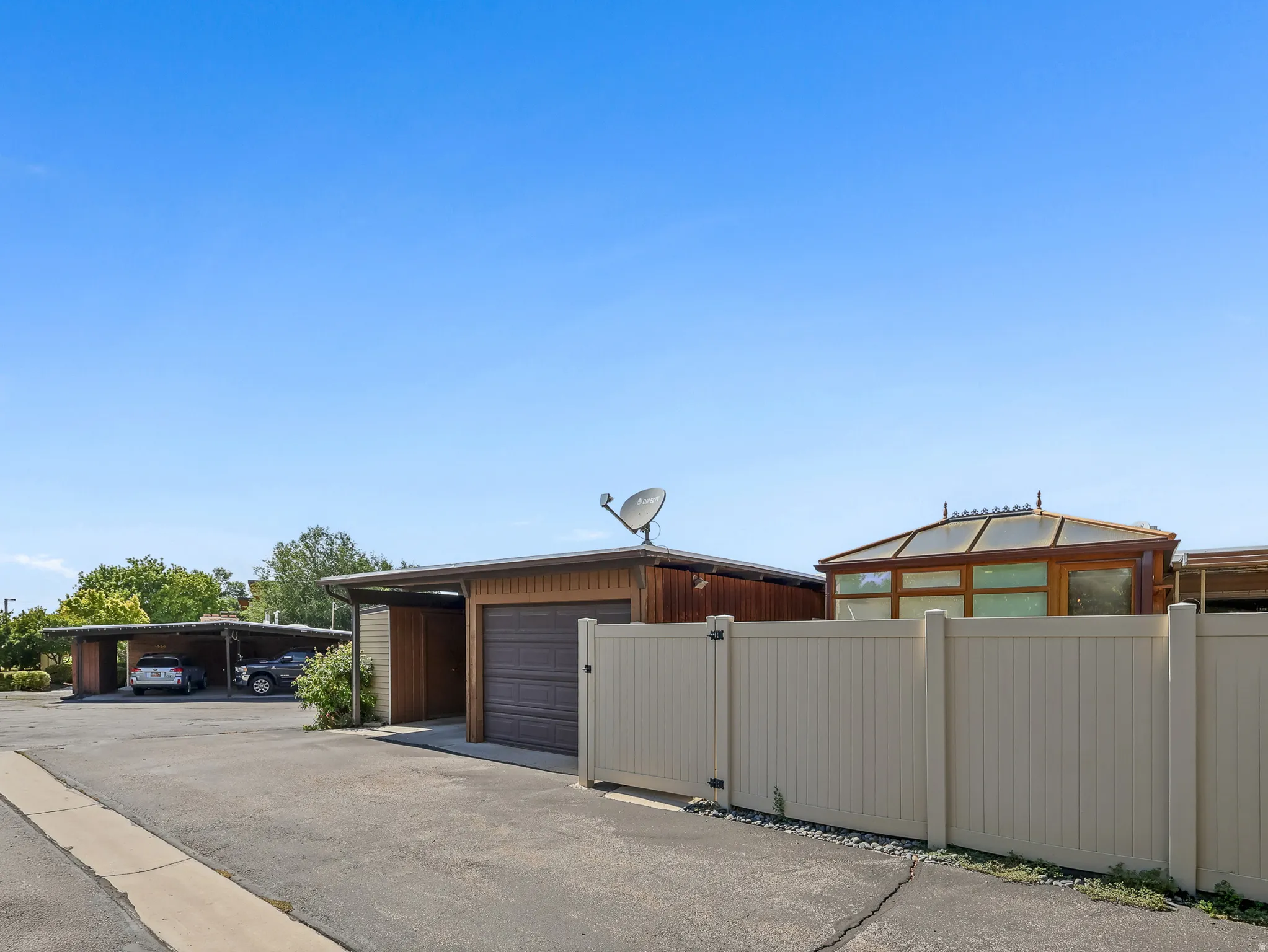 Detached garage with a roll-up door, carport, and private fence