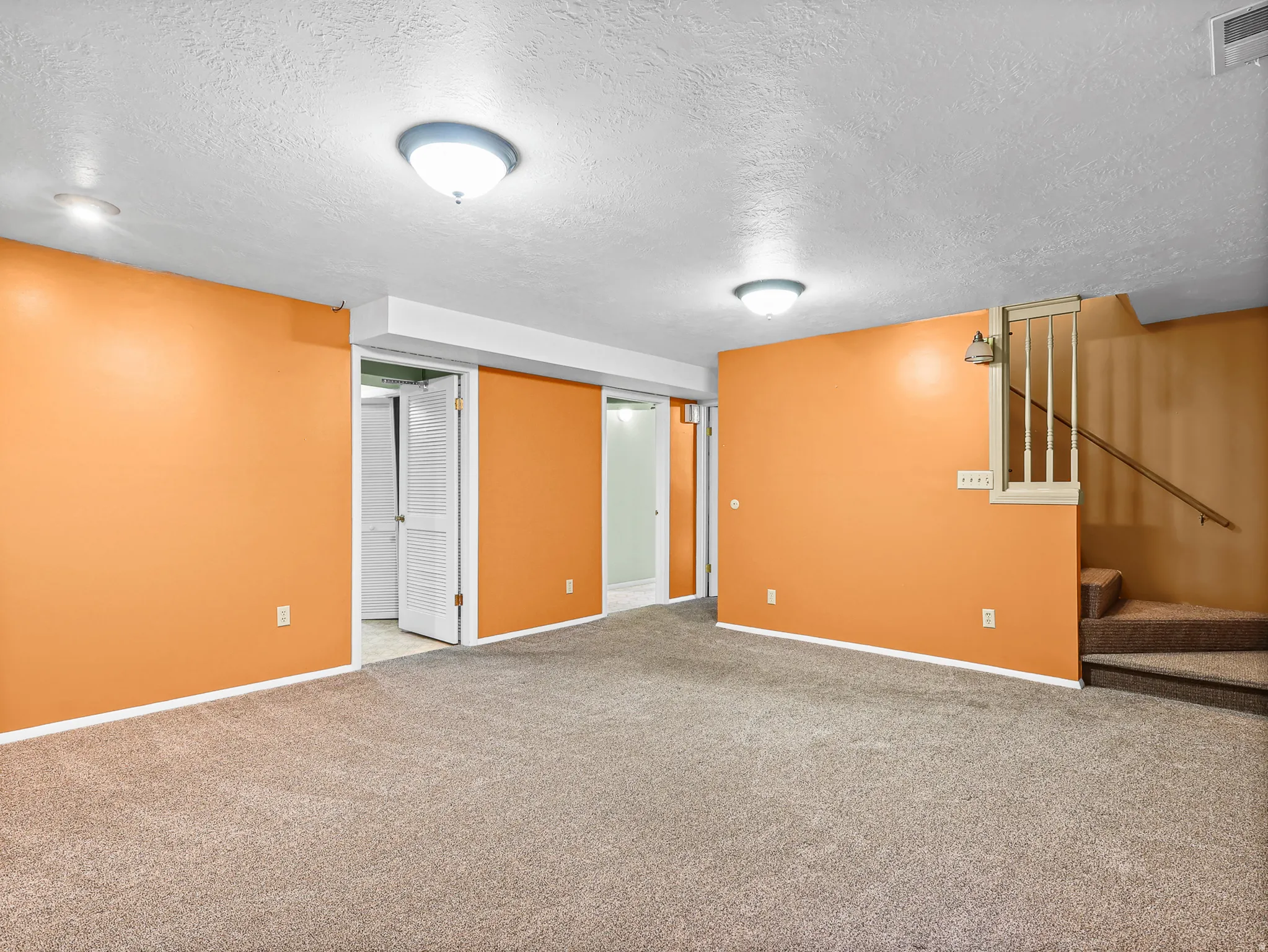 Carpeted room featuring orange walls and recessed lighting