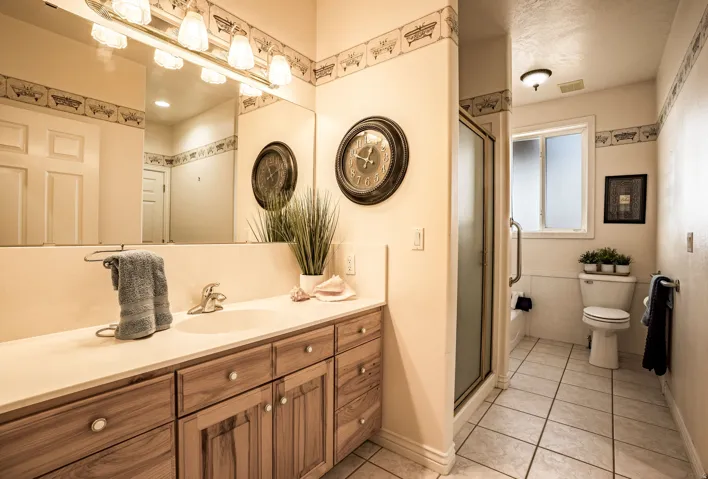 Bathroom featuring a wood-finish vanity with an integrated sink and a large wall mirror with overhead lighting