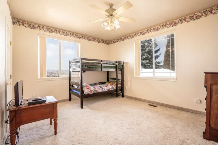 Bright room featuring two large windows, neutral-toned walls, and a ceiling fan