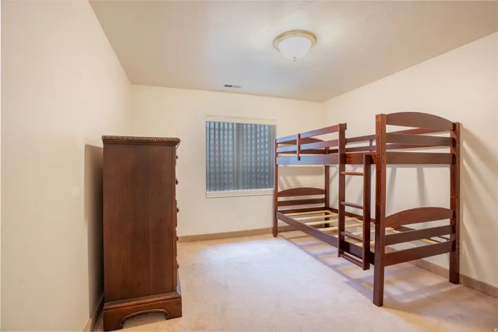 Carpeted room featuring a window with horizontal blinds, a ceiling-mounted light fixture, and neutral wall paint