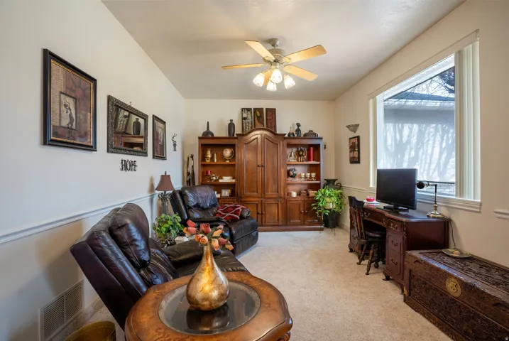 Spacious room featuring vaulted ceilings, a ceiling fan with integrated lighting, and a large window with white trim