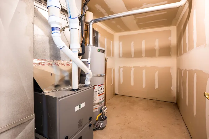 Utility room featuring a water heater, furnace, and exposed ductwork