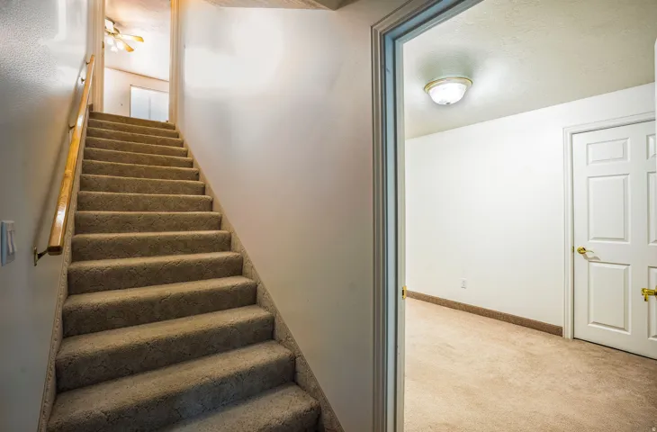 Carpeted staircase with wooden handrail