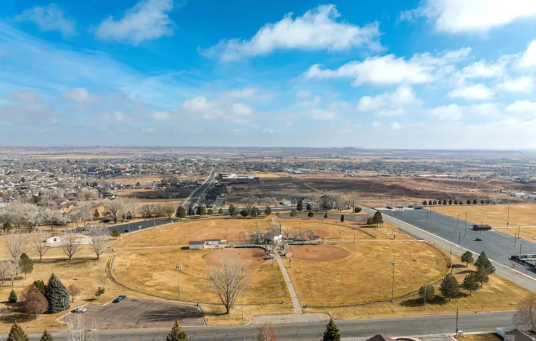 Expansive aerial perspective showcasing a community park with two baseball diamonds, surrounding green spaces, and a large paved parking area