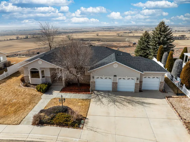 Ranch-style residence featuring a three-car garage with white paneled doors, a bay window with a curved top, and a stone facade accent