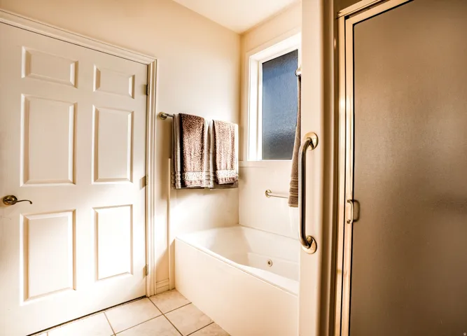 Ensuite Bathroom featuring a jetted tub, ceramic tile flooring, and an enclosed shower with a frosted glass door