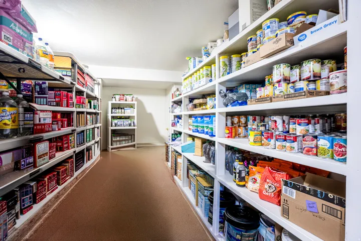 Dedicated storage room featuring extensive built-in shelving, white painted walls, and durable flooring