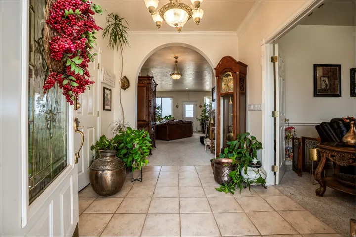 Foyer featuring light-toned square floor tiles, a decorative entry door with frosted glass, and an arched doorway leading to an interior space