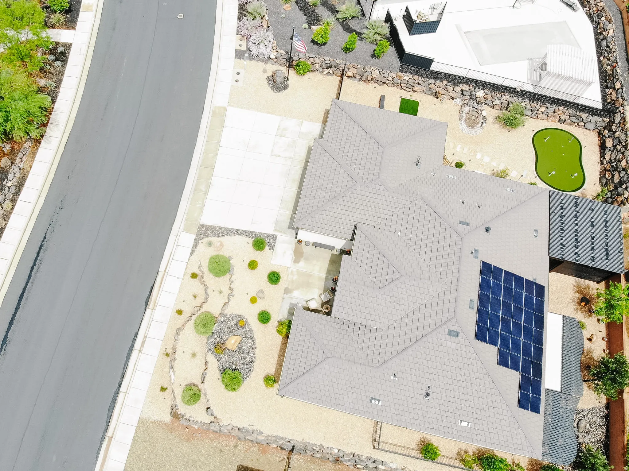 Solar panel array, putting green, concrete driveway, xeriscaped front yard, and rock landscaping