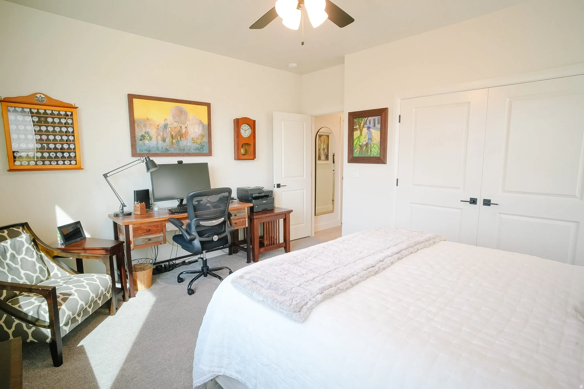 Carpeted room featuring a ceiling fan with integrated lighting, a paneled door, and dual closet doors with matte black hardware