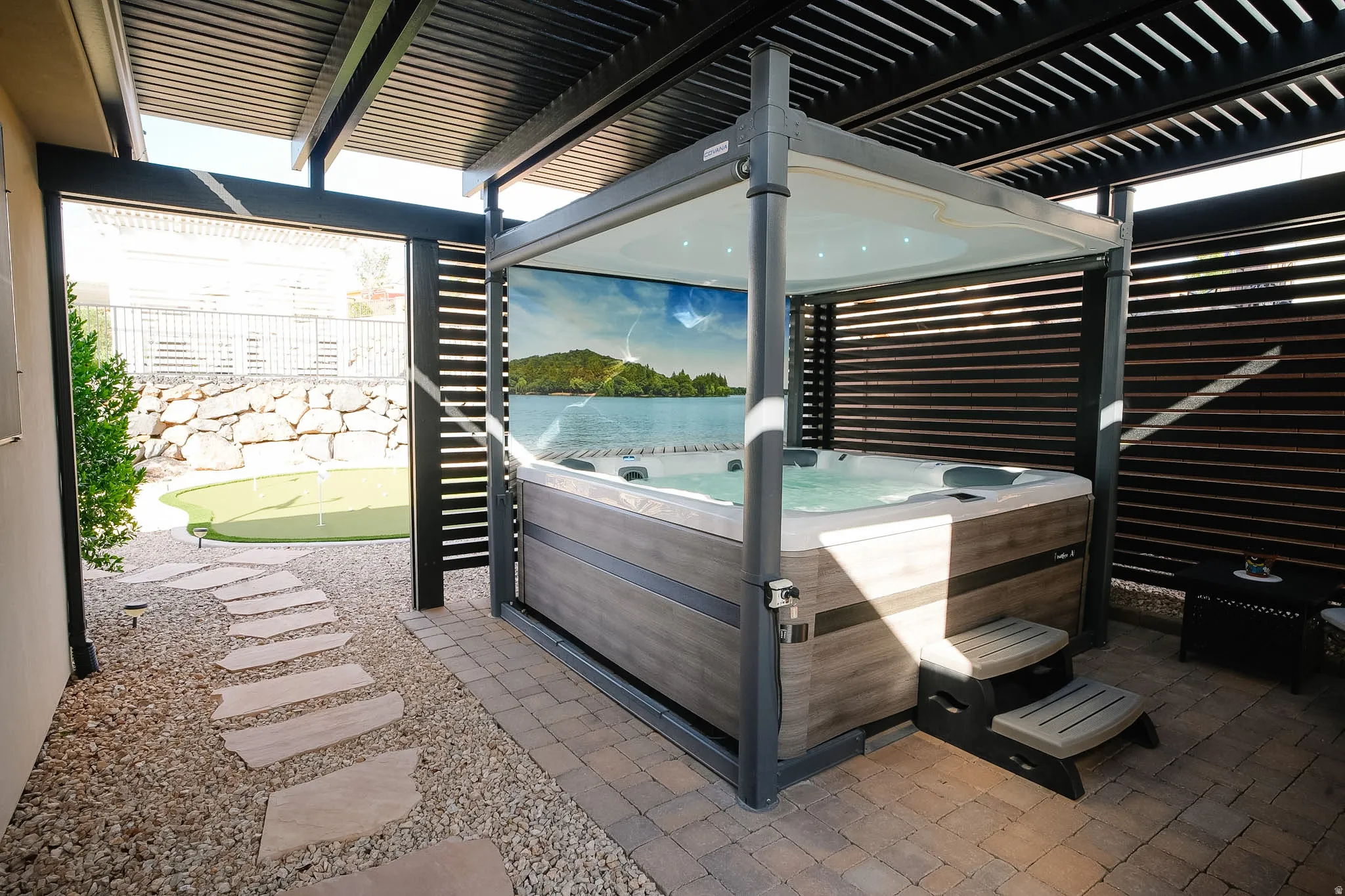 Private spa area featuring a built-in hot tub with a wood-finish surround, under a louvered pergola, and privacy screens