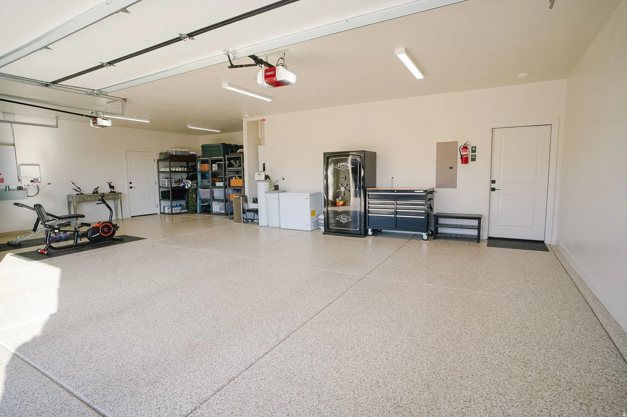 Spacious garage featuring a finished epoxy floor, multiple overhead garage door openers, and recessed lighting