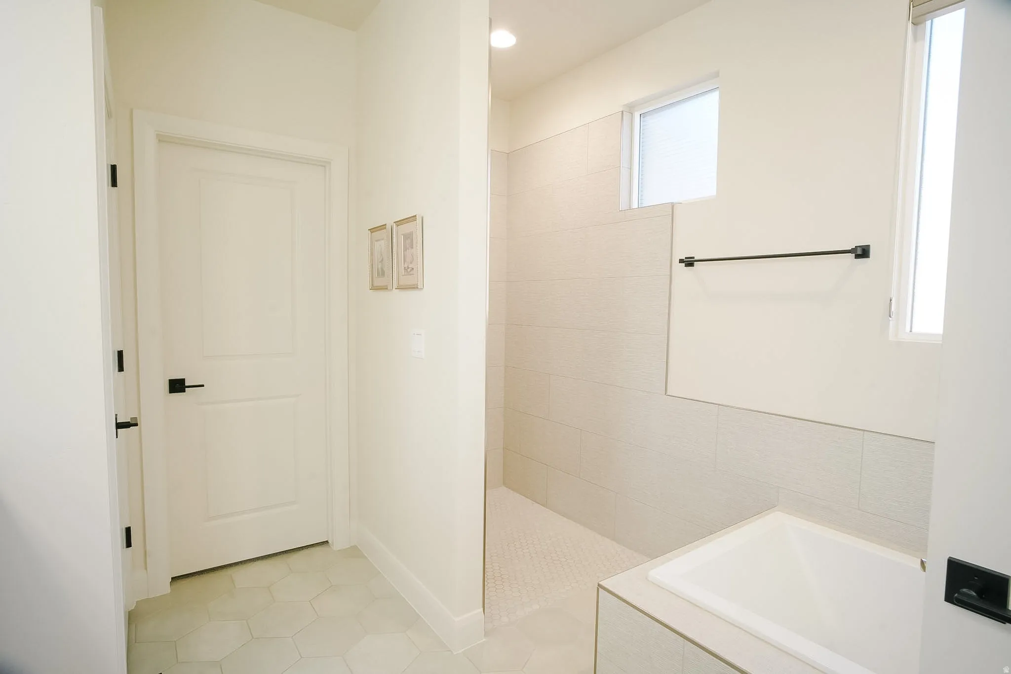 Bathroom featuring a built-in soaking tub, walk-in shower with tiled walls and floor, and hexagon tile flooring
