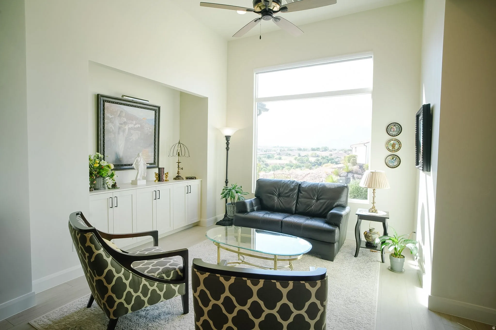 Living area featuring high ceilings, a built-in storage cabinet with white shaker-style doors, and expansive windows
