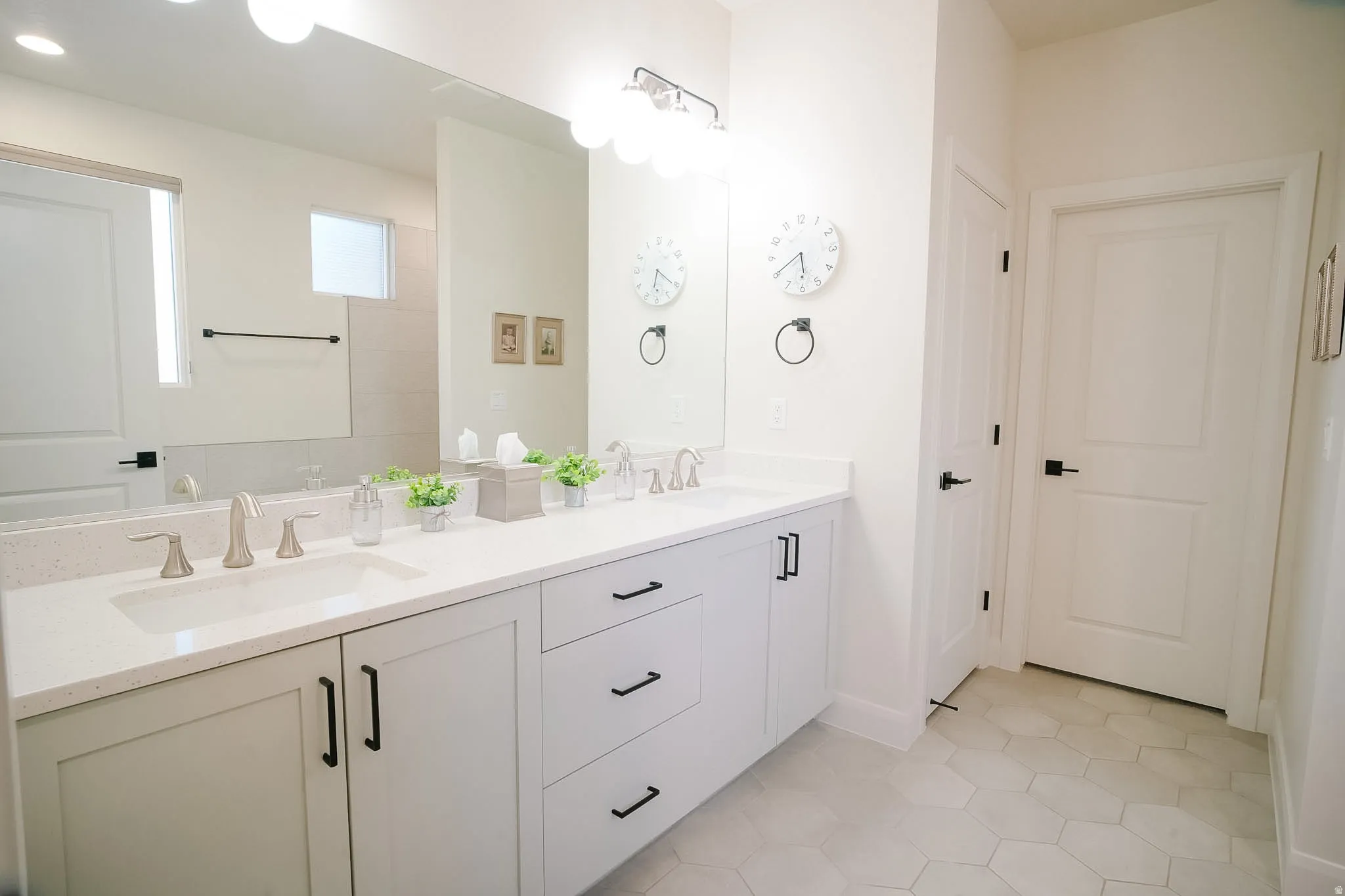 Double vanity with light gray cabinetry, matte black hardware, and an expansive countertop