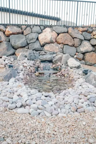 Water feature with a stone basin, surrounded by decorative pebbles and gravel