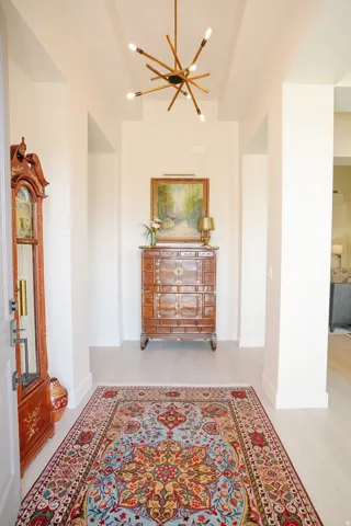 Entryway featuring a modern sputnik chandelier, recessed ceiling detail, light wood-finish flooring, and crisp white walls